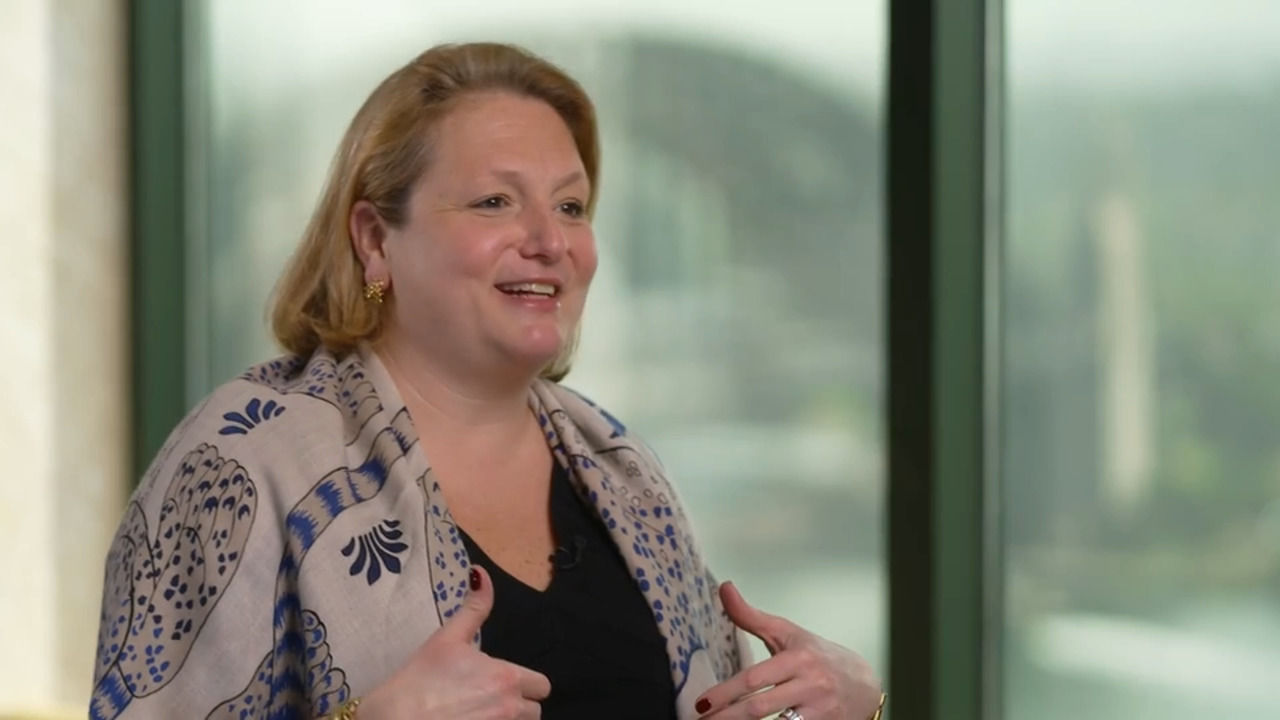 Alisa wood discussing Private Equity in front of a scenic view in a high-rise conference room. 